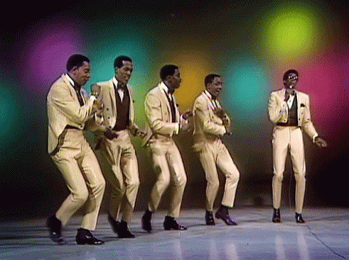 A Group Of Men In Suits Are Dancing And Singing Into Microphones GIF