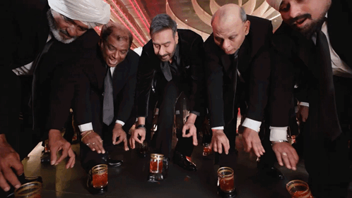A Group Of Men In Suits Are Kneeling Down With Their Hands On A Table GIF