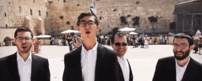 A Group Of Men In Suits Are Singing In Front Of A Stone Wall . GIF