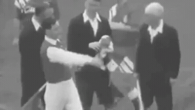 A Group Of Men In Suits Are Standing Around A Baseball Player . GIF