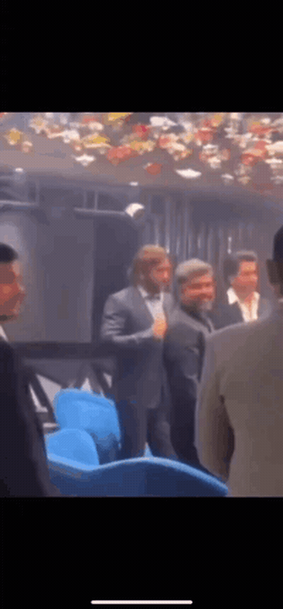 A Group Of Men In Suits Are Standing In A Dark Room . GIF