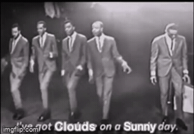A Group Of Men In Suits Are Walking In A Row . GIF