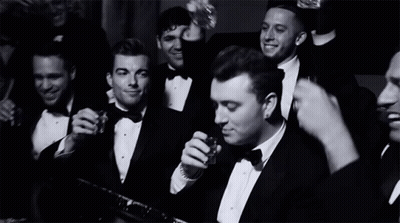 A Group Of Men In Tuxedos And Bow Ties Are Drinking And Smoking GIF