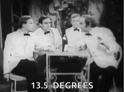 A Group Of Men In Tuxedos Are Sitting At A Table Talking To Each Other . GIF