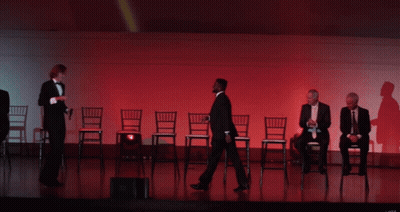 A Group Of Men In Tuxedos Are Sitting In Chairs On Stage GIF