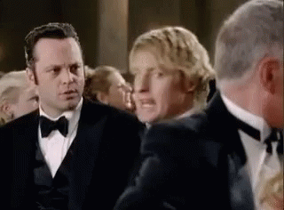 A Group Of Men In Tuxedos Standing Next To Each Other In A Crowd . GIF