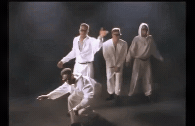 A Group Of Men In White Clothes Are Dancing Together On A Stage . GIF