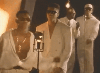 A Group Of Men In White Suits And Sunglasses Are Standing Next To Each Other In Front Of A Microphone . GIF