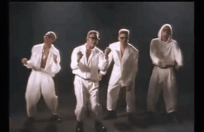 A Group Of Men In White Suits Are Dancing In A Line . GIF