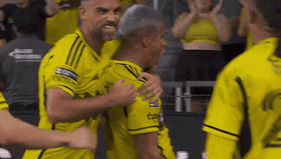 A Group Of Men In Yellow Jerseys Are Hugging Each Other . GIF