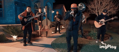 A Group Of Men Playing Instruments In Front Of A House With A Watermark That Says Imgplay GIF