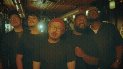 A Group Of Men Posing For A Photo With One Wearing A Red Hat GIF