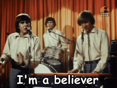 a group of men singing into microphones with the words " i 'm a believer " written on the bottom