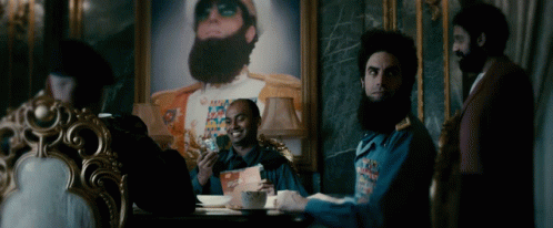 Men Sitting Around Table In Front Of Painting GIF