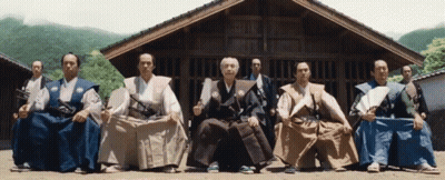A Group Of Men Sitting In Front Of A Building GIF
