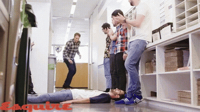 A Group Of Men Standing Around A Man Laying On The Floor With Esquire Written On The Bottom Right GIF