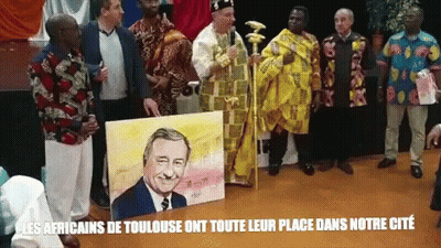 A Group Of Men Standing Around A Painting Of A Man With The Words Les Africains De Toulouse On The Bottom Right GIF