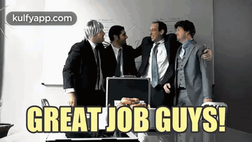 A Group Of Men Standing Around A Table With The Words Great Job Guys Written On It GIF
