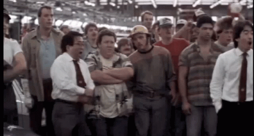 A Group Of Men Standing In A Line With Their Arms Crossed And One Man Wearing A Hard Hat GIF