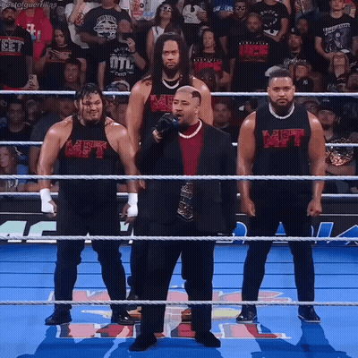 A Group Of Men Standing In A Wrestling Ring With One Wearing A Shirt That Says Met On It GIF