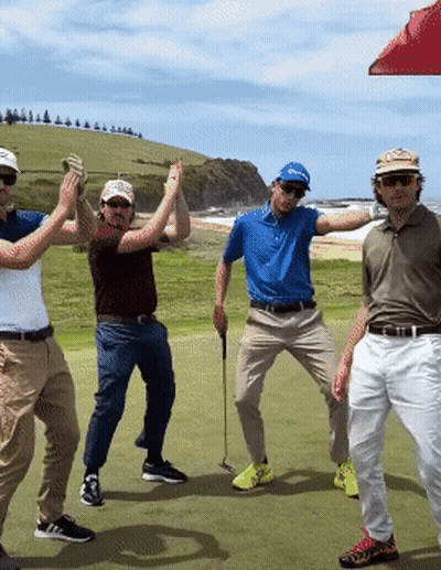 A Group Of Men Standing On A Golf Course With One Wearing A Blue Shirt That Says ' Taylormade ' On It GIF