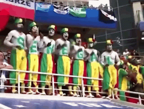 A Group Of Men Wearing Green Yellow And Red Pants Are Standing In A Row GIF