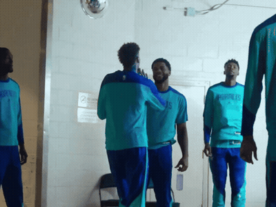 A Group Of Men Wearing Hornets Shirts Are Standing In A Hallway GIF