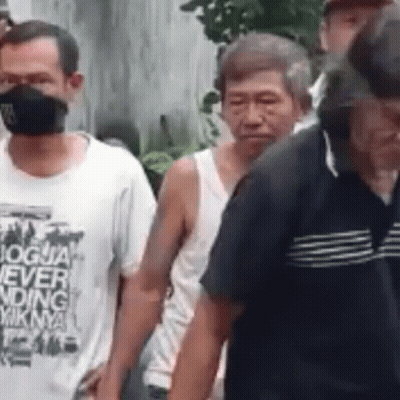 A Group Of Men Wearing Masks Are Walking In A Line . GIF