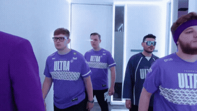 A Group Of Men Wearing Purple Ultra Shirts Are Walking Down A Hallway GIF