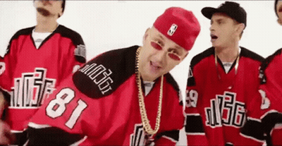 A Group Of Men Wearing Red And Black Hockey Jerseys And Hats Are Standing Next To Each Other . GIF