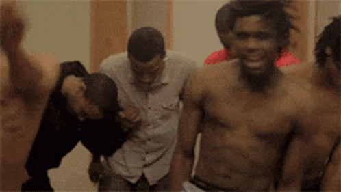 A Group Of Men Without Shirts Are Standing In A Room GIF