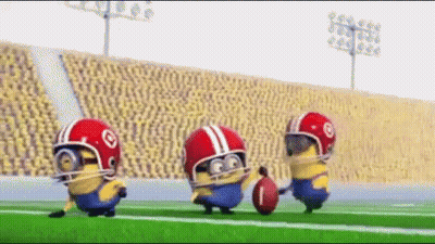 A Group Of Minions Wearing Helmets And Holding A Football On A Field GIF