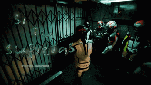 A Group Of Motorcycle Riders Are Standing In Front Of A Gate That Says ' Suspects ' GIF
