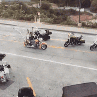 A Group Of Motorcycles Are Driving Down The Street GIF