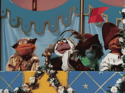 A Group Of Muppets Are On A Stage With Flowers And A Flag In The Background GIF