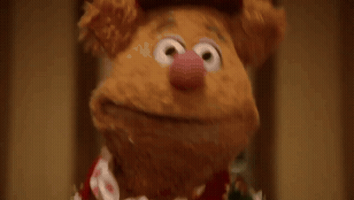 A Group Of Muppets Are Standing In A Hallway And One Of Them Is Wearing A Sweater That Says Muppets GIF