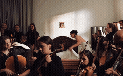 A Group Of Musicians Are Playing In A Room With A Woman In The Background GIF