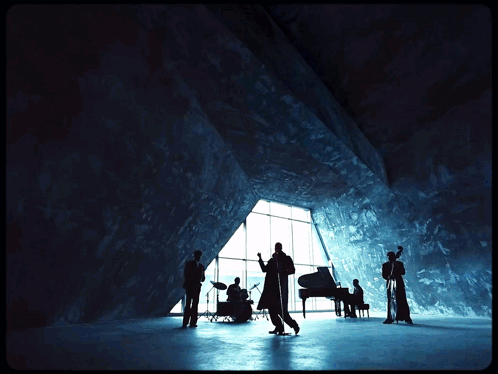 A Group Of Musicians Are Standing In Front Of A Large Window GIF