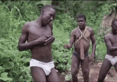 A Group Of Naked Men In Underwear Are Standing In A Forest . GIF