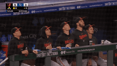 A Group Of Orioles Players Sit In The Dugout Watching The Game GIF