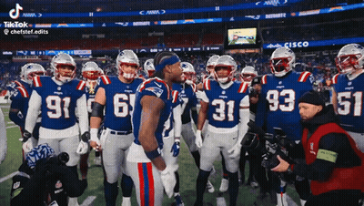 A Group Of Patriots Football Players Stand On The Field Talking To Each Other GIF