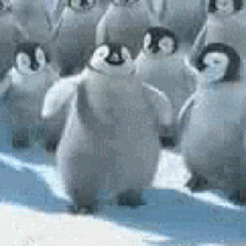 A Group Of Penguins Are Standing On Top Of A Snowy Surface . GIF