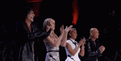 A Group Of People Are Applauding On A Stage . GIF