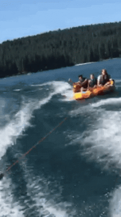 A Group Of People Are Being Towed By A Boat In A Lake GIF