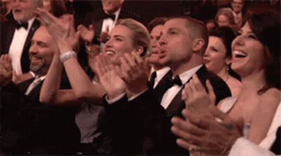 A Group Of People Are Clapping Their Hands In A Crowd . GIF