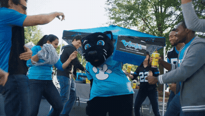 A Group Of People Are Dancing Around A Panther Mascot Wearing A Blue Shirt With The Number 22 On It GIF