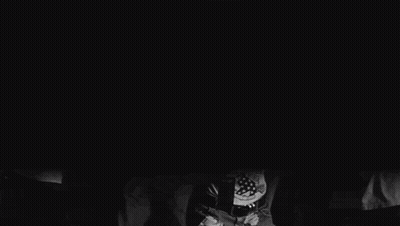 A Group Of People Are Dancing In A Dark Room And One Of Them Is Holding A Bottle Of Beer GIF