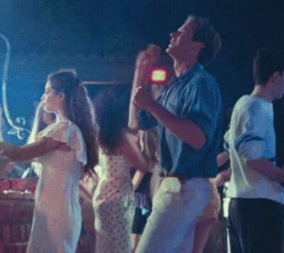 A Group Of People Are Dancing In A Dark Room With A Blue Light Behind Them GIF