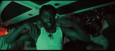 A Group Of People Are Dancing In A Dark Room With A Green Light Behind Them GIF