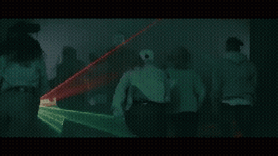 A Group Of People Are Dancing In A Dark Room With Green Lights Coming Out Of The Ceiling . GIF